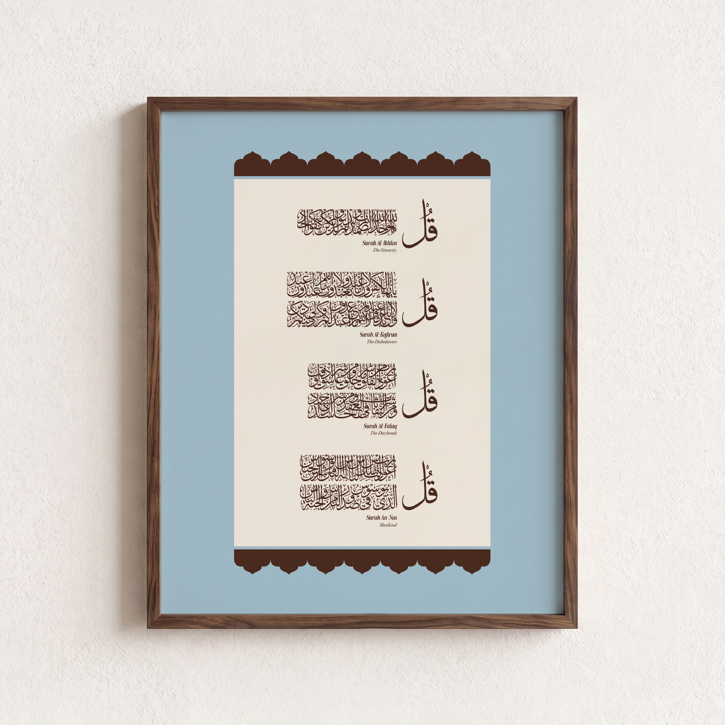 Framed Islamic wall art featuring Arabic calligraphy of the 4 Quls, presented in a dark brown wooden frame against a textured off-white wall.