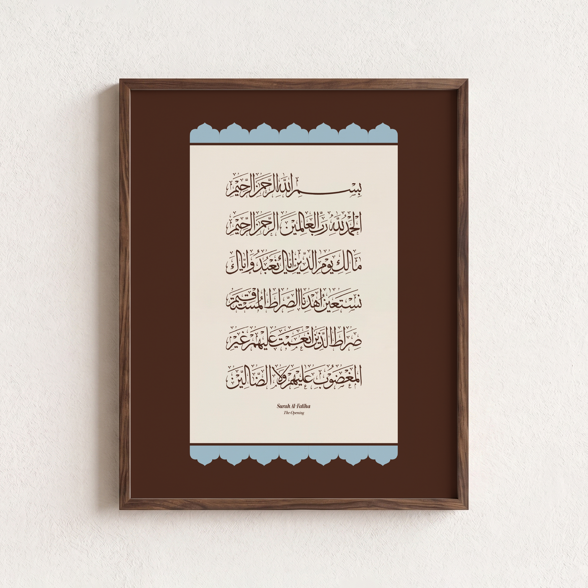 Framed Islamic wall art featuring Arabic calligraphy of Surah Al-Fatiha, presented in a dark brown wooden frame against a textured off-white wall.