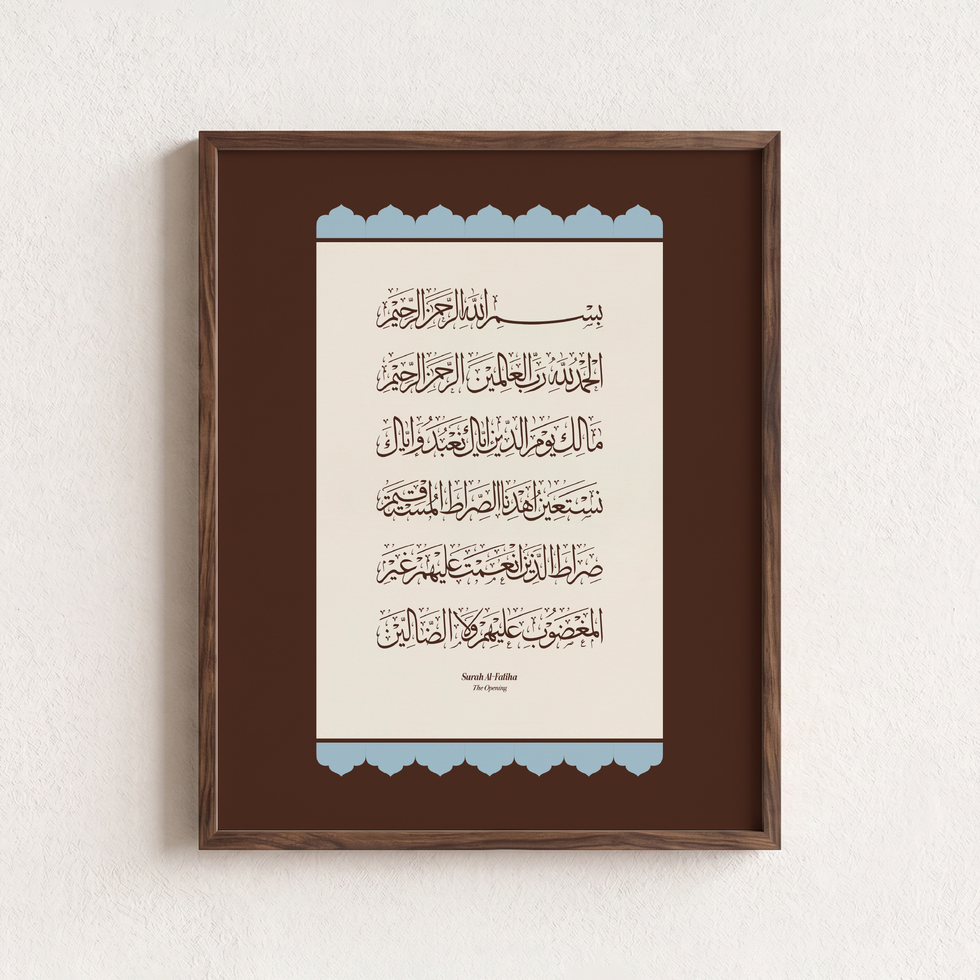 Framed Islamic wall art featuring Arabic calligraphy of Surah Al-Fatiha, presented in a dark brown wooden frame against a textured off-white wall.