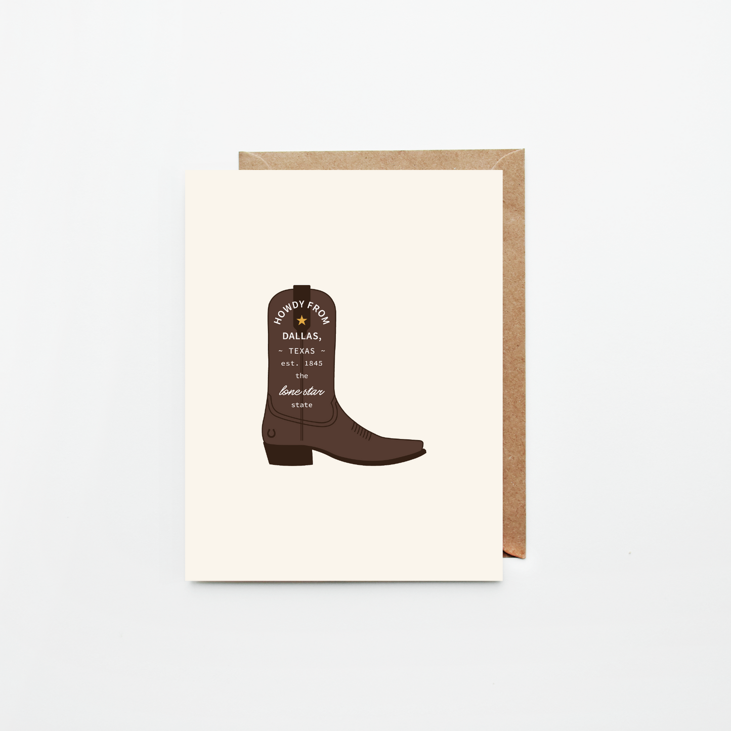 A light cream greeting card featuring an illustration of a brown cowboy boot with 'Howdy from Dallas' text, shown with a brown kraft envelope on a white background.